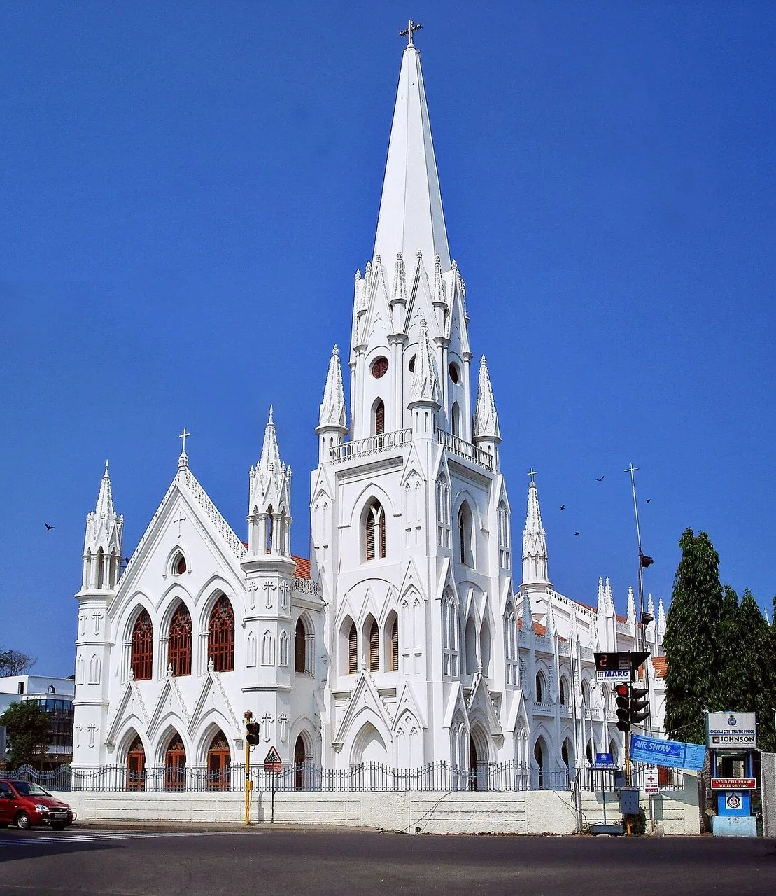 Fachada branca neogótica da basílica de Santhome, com torre alta, cruzes e céu azul.