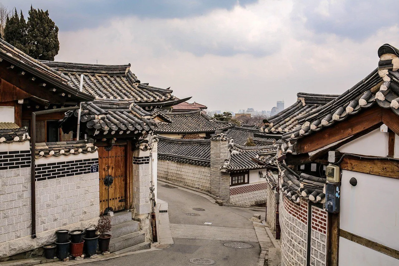 Calle inclinada de Bukchon con casas hanok, muros de ladrillo y tejados curvos.