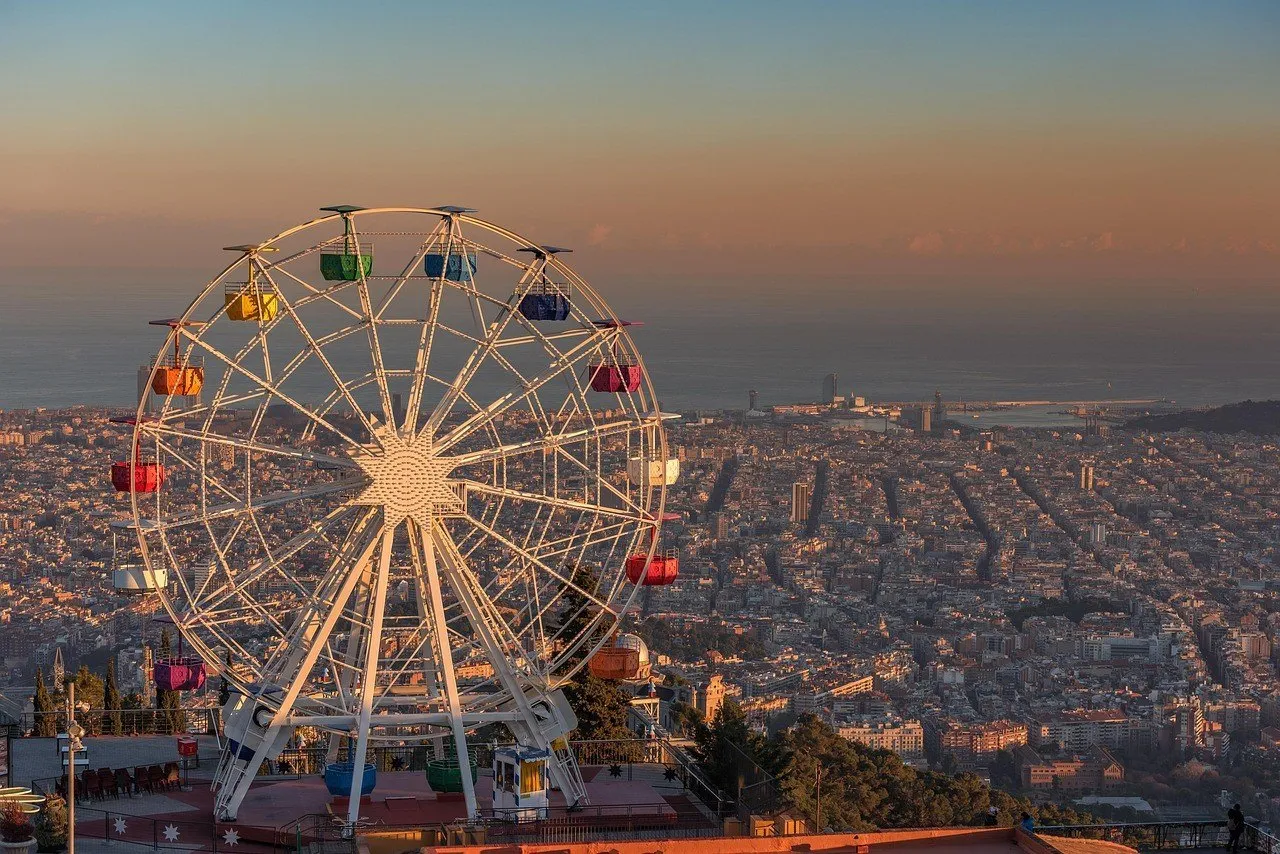 Tibidabo Ferris wheel in the foreground, with Barcelona and the Mediterranean in golden light.
