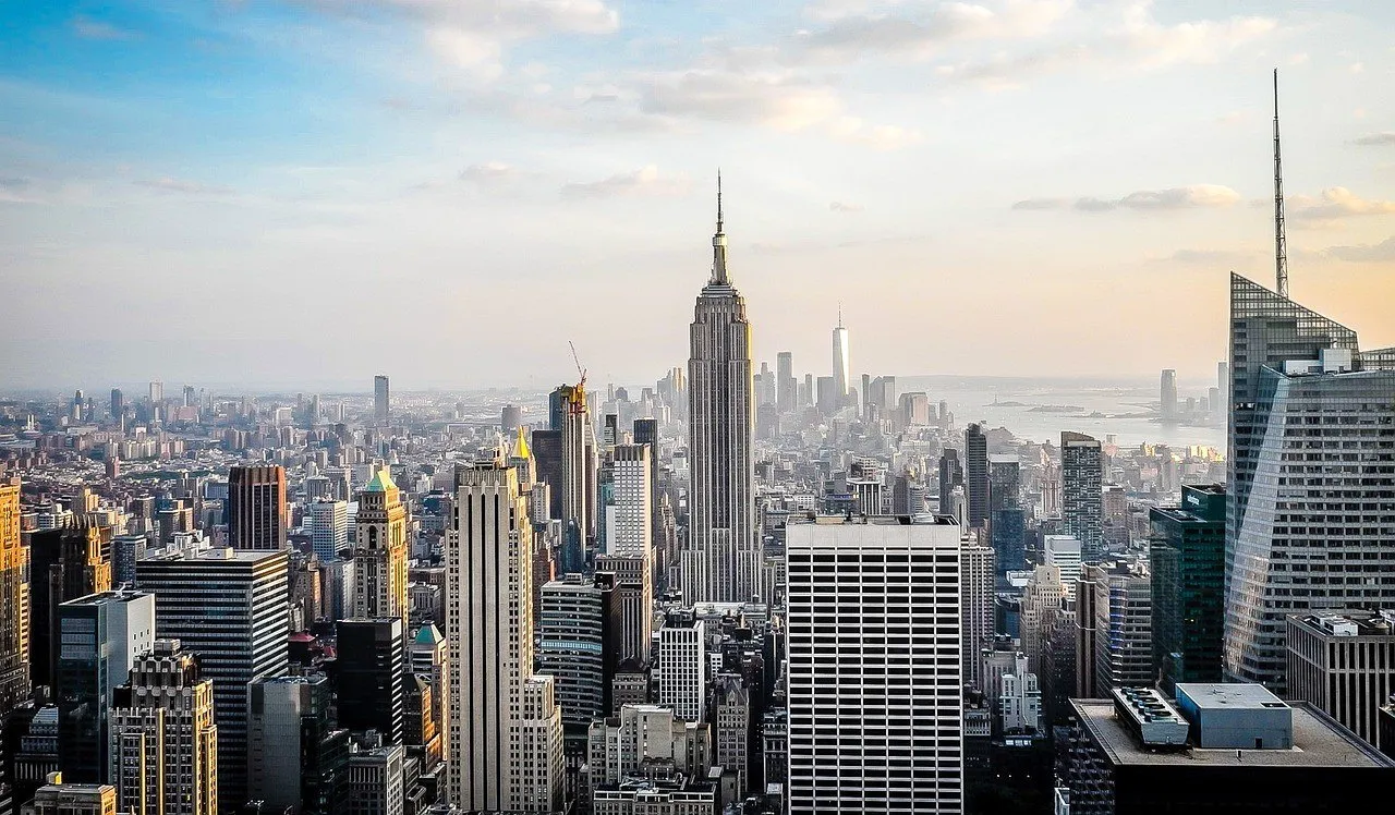 Empire State Building no centro do horizonte de Manhattan visto do alto, com edifícios de Midtown em volta e o rio ao fundo.