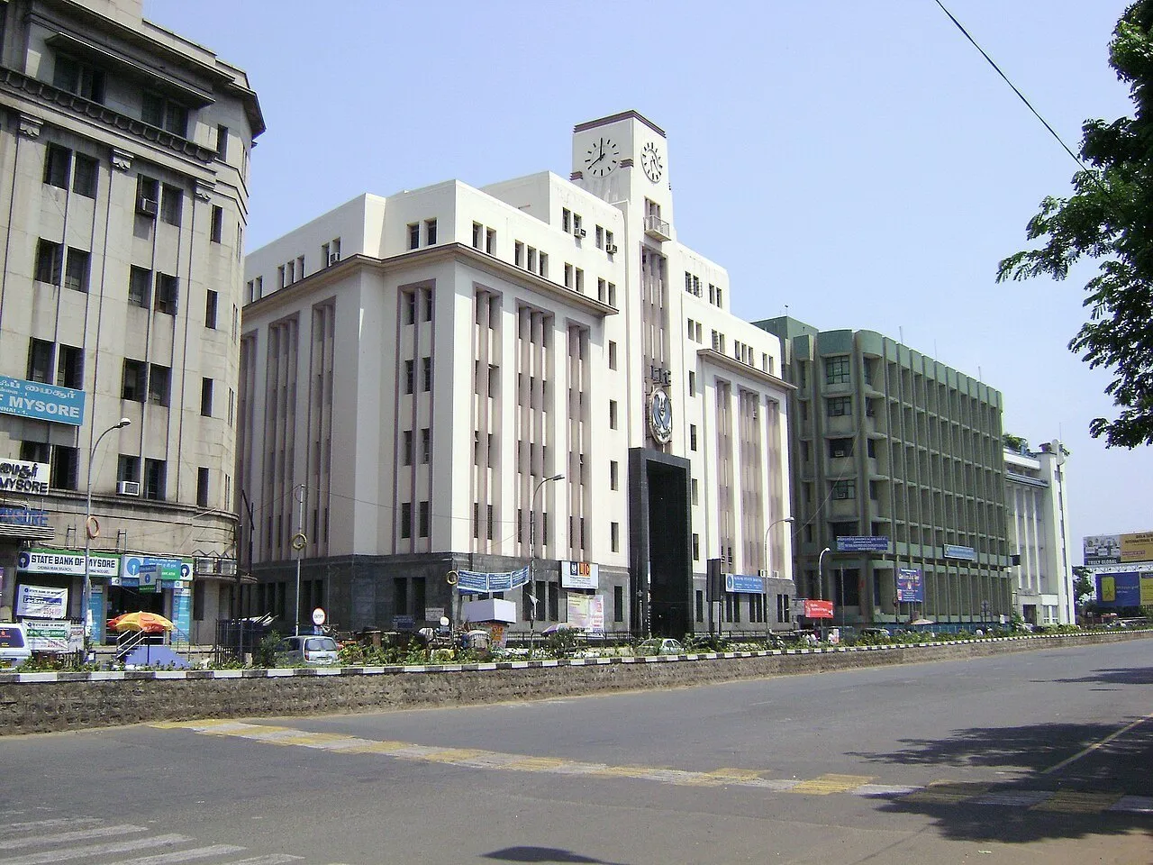 Edifícios comerciais com torre de relógio em Parry’s Corner, Chennai, diante de uma avenida.
