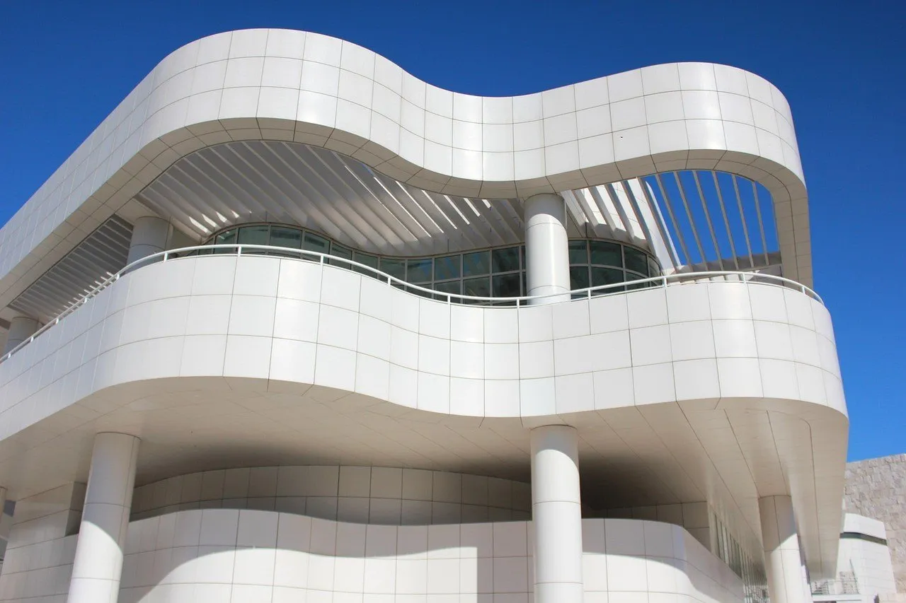 Detalhe da arquitetura branca do Getty Center, com curvas, colunas e terraços sob céu azul.