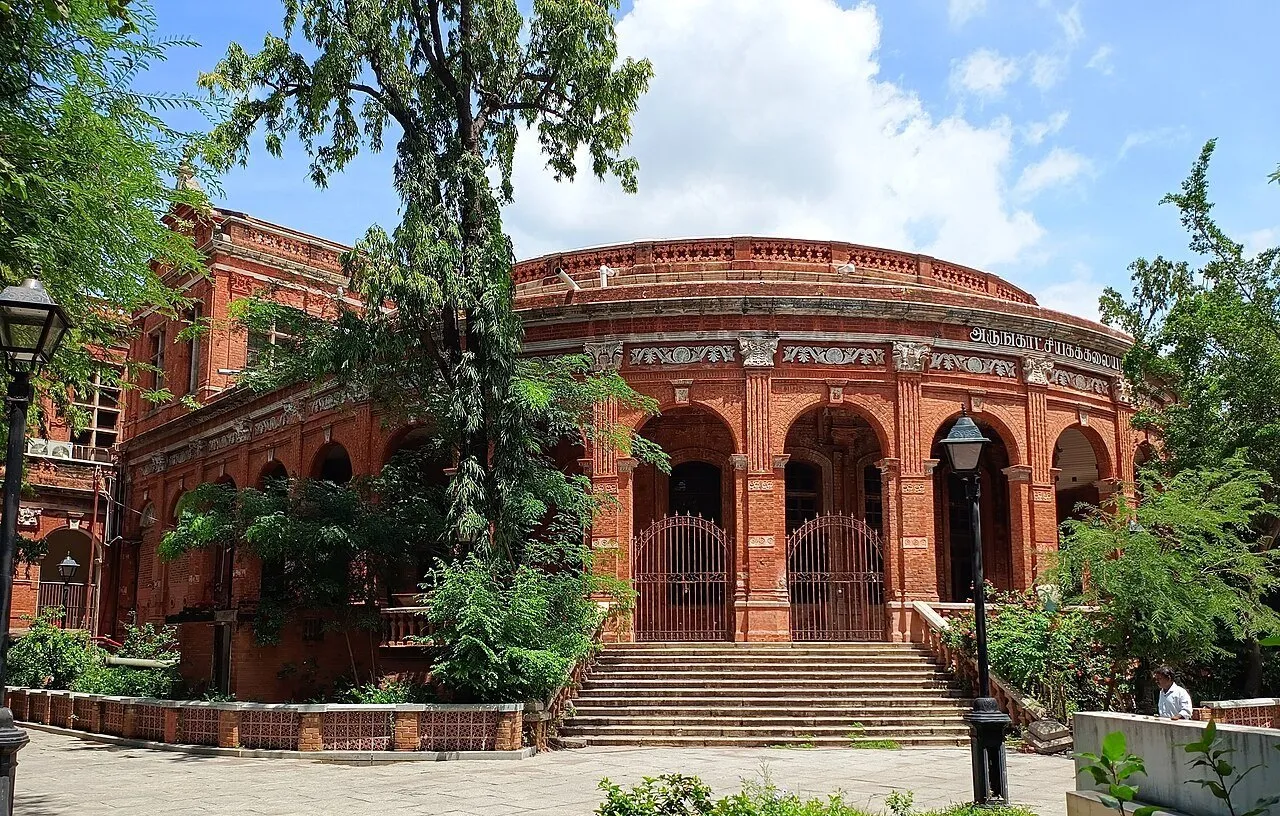 Teatro de tijolos vermelhos do Government Museum, com arcos, escadaria e árvores ao redor.
