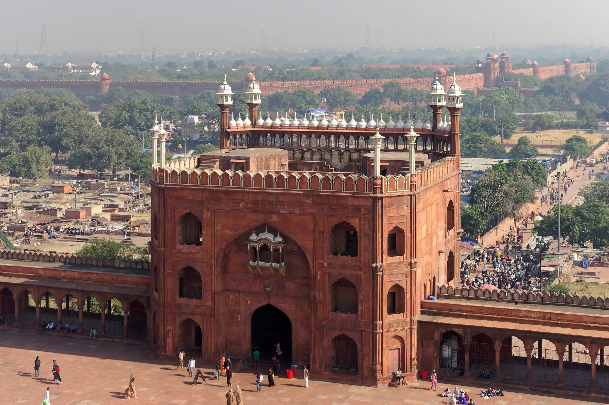 Portón este de la Jama Masjid, en Delhi, visto desde arriba, con el patio abajo y las murallas del Fuerte Rojo al fondo.