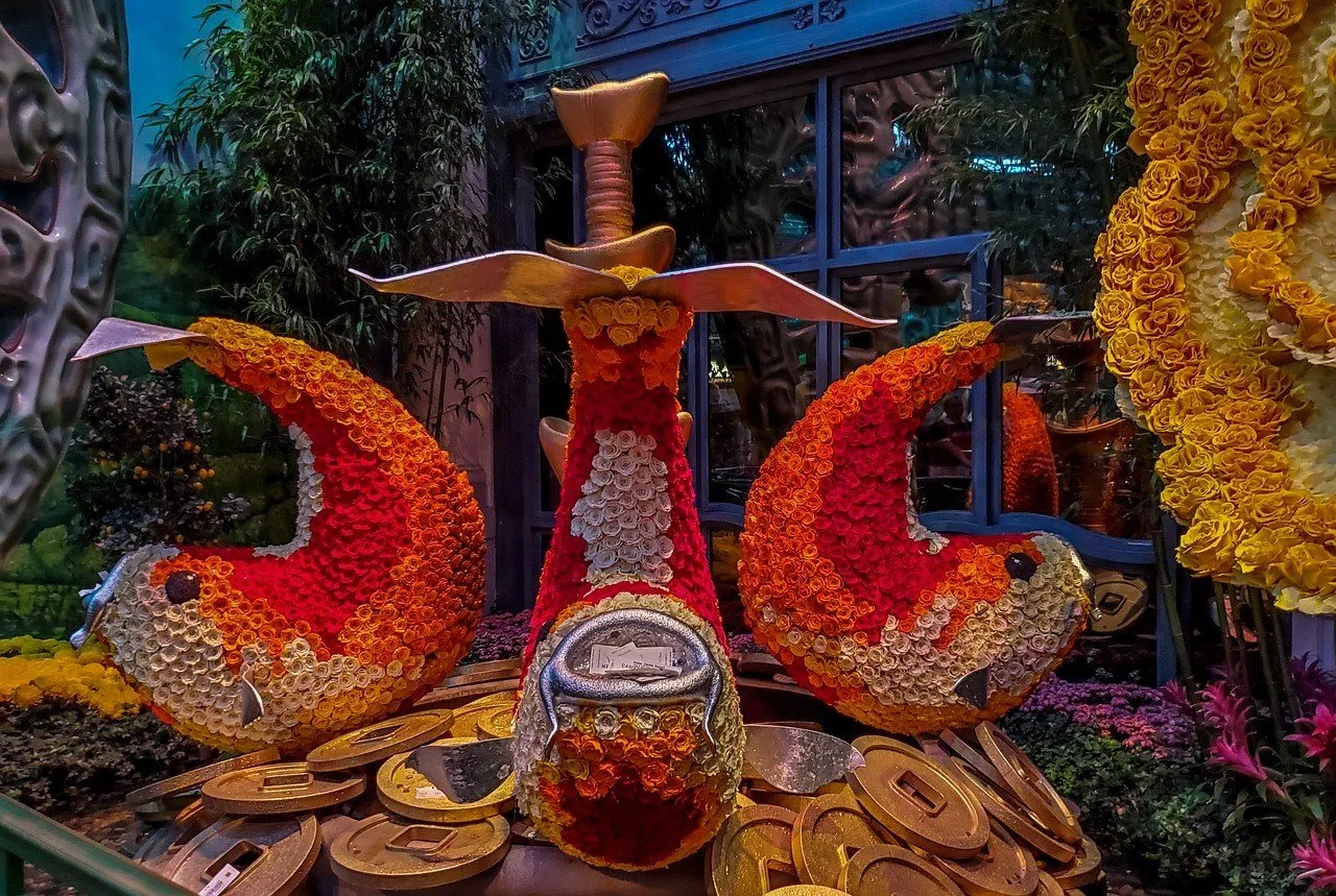 Red and orange decorative fish made of flowers among themed coins at the Bellagio Conservatory.