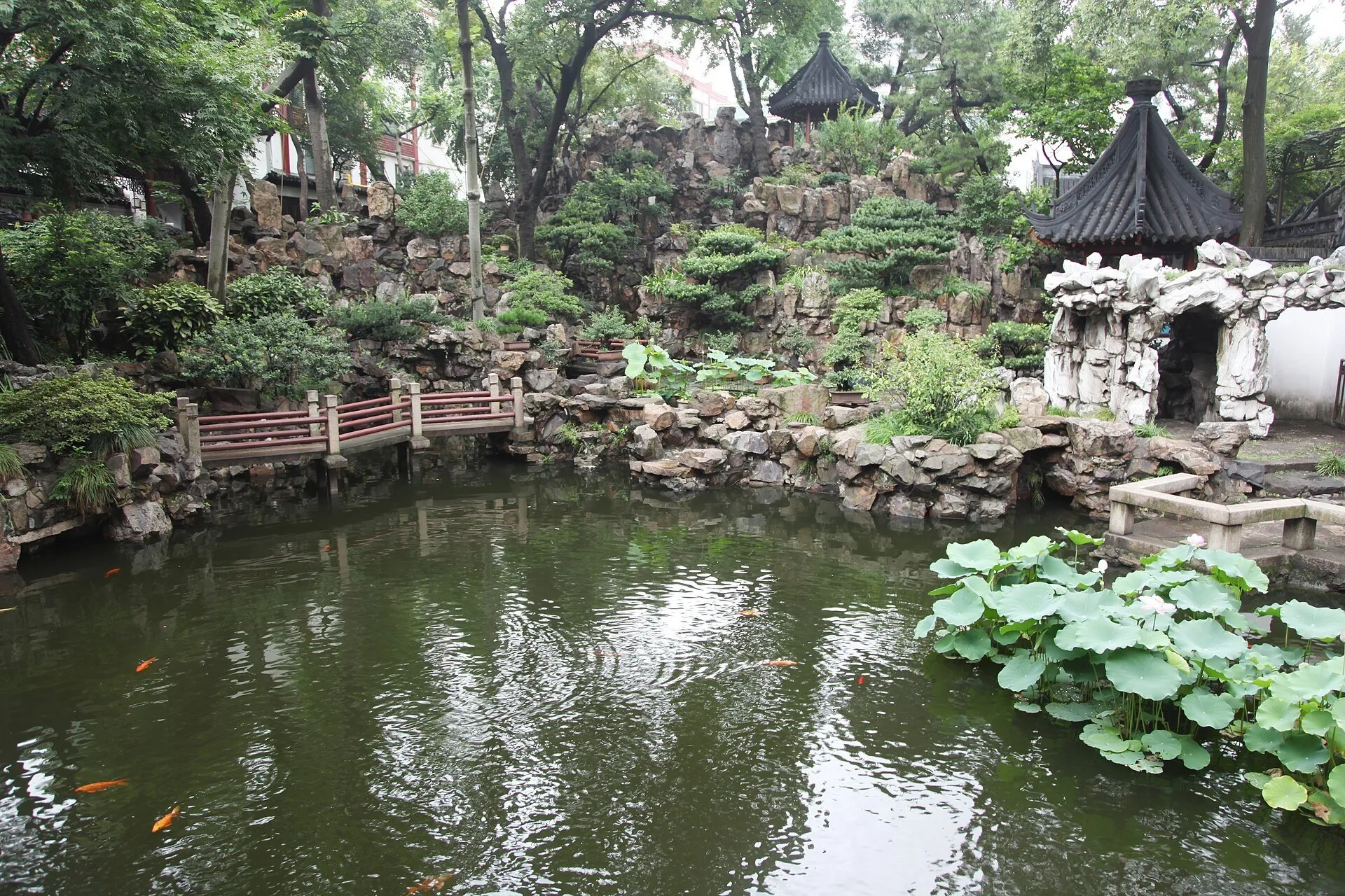 Pond with carp, rocks, trees and dark-tiled pavilions inside Yu Garden.