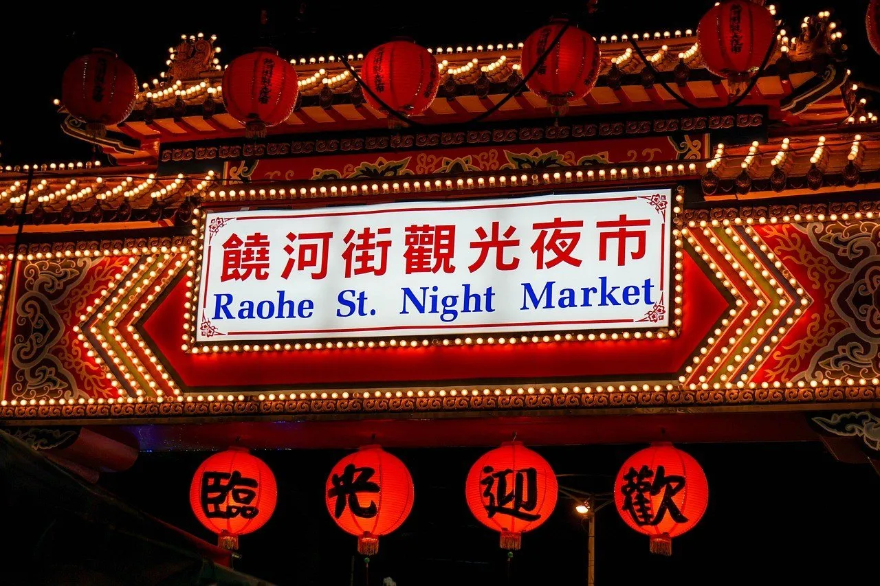 Portal iluminado do Mercado Noturno de Raohe, com lanternas vermelhas e letreiro em chinês e inglês.