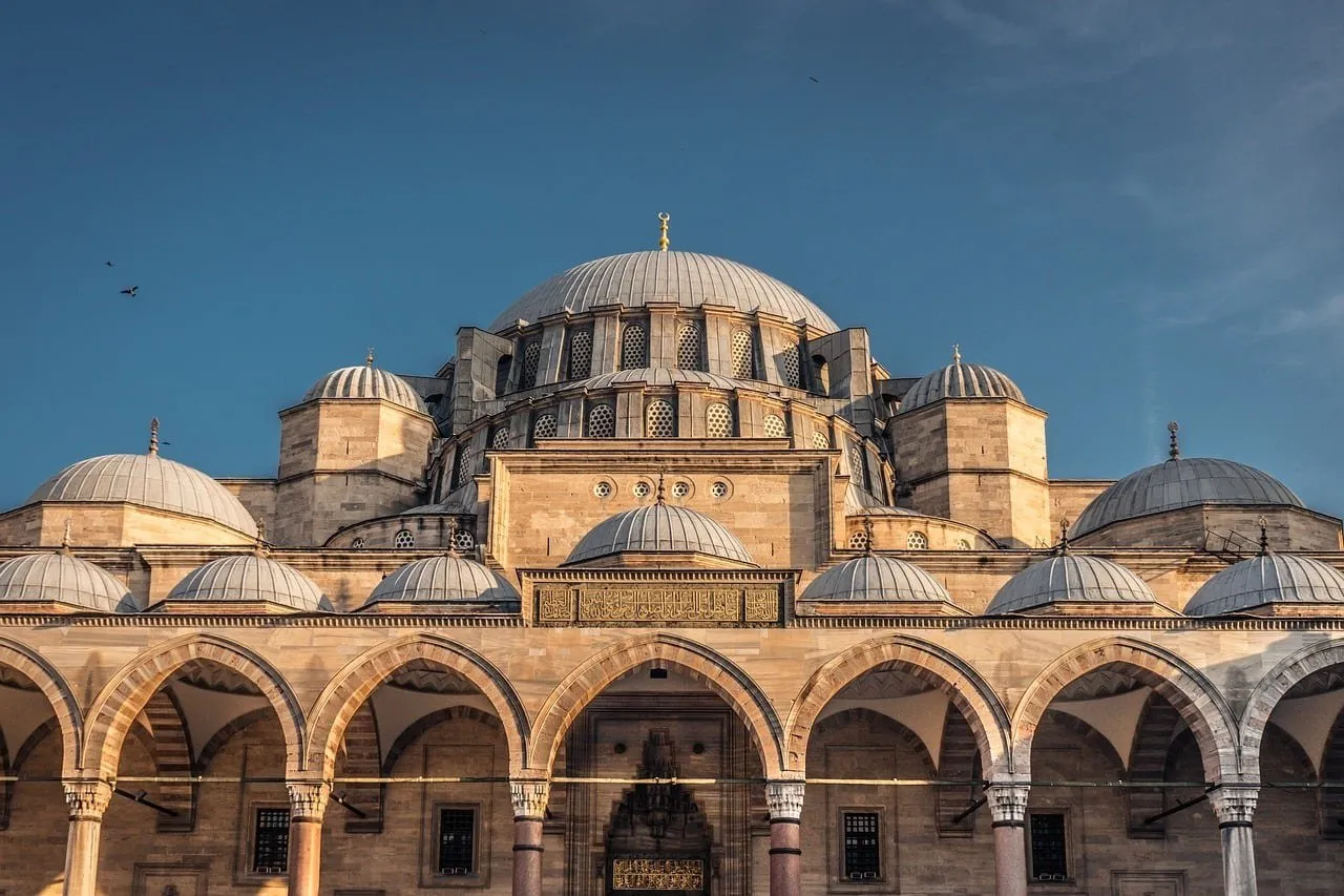 Cúpula central y cúpulas menores de la Mezquita de Süleymaniye vistas desde el patio, con arcadas de piedra en primer plano.