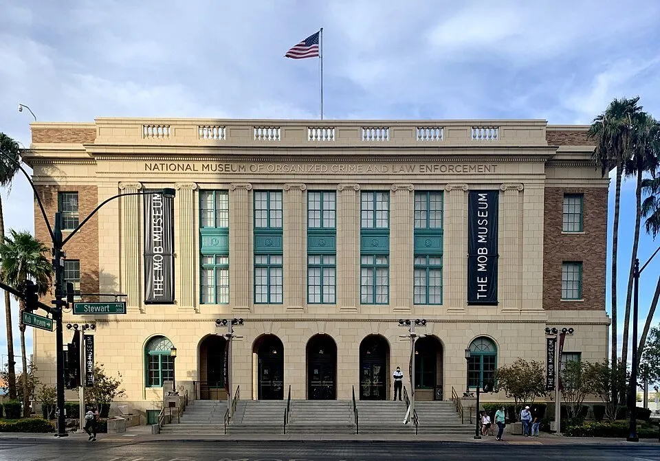 Pale Mob Museum facade with columns, green windows, steps and a United States flag.