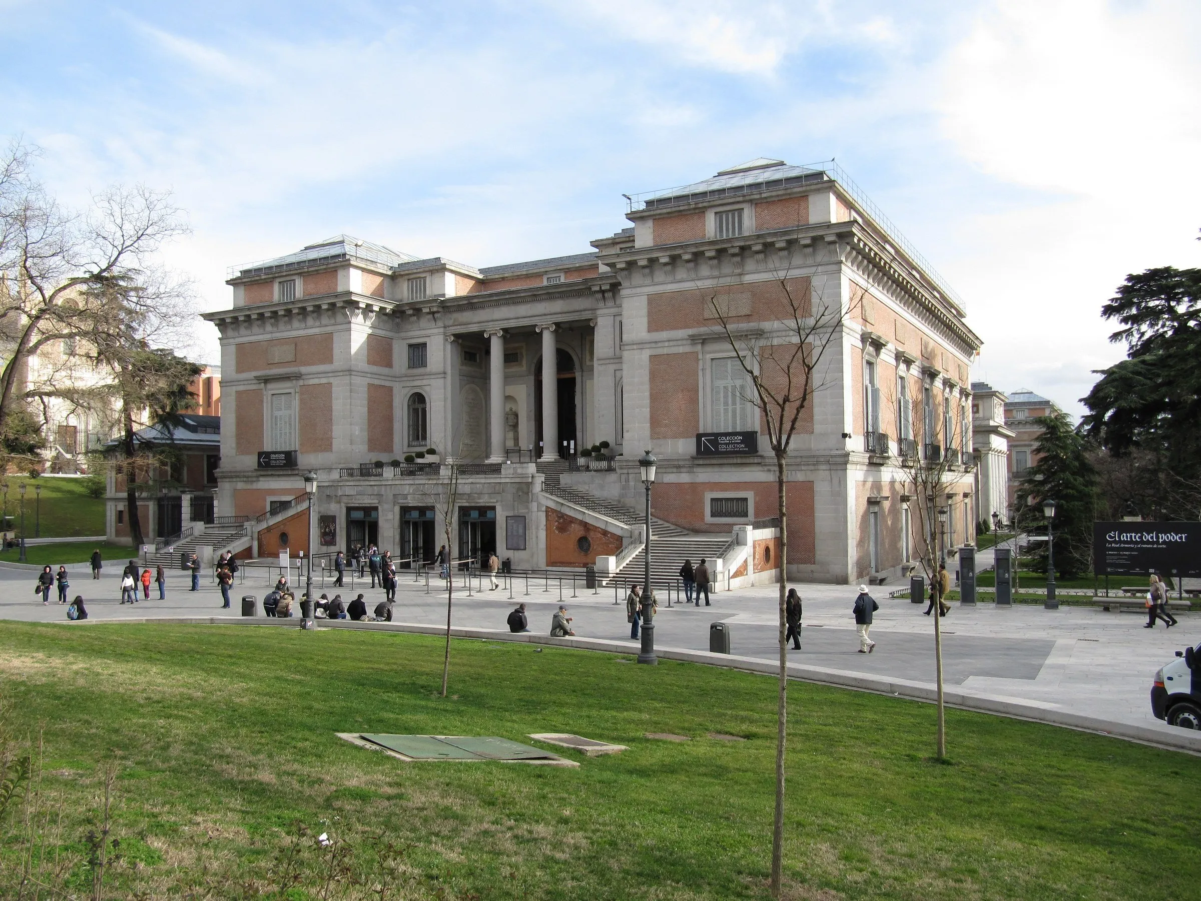 Exterior facade of the Prado Museum, with columns, stairways, a lawn and small figures of visitors.