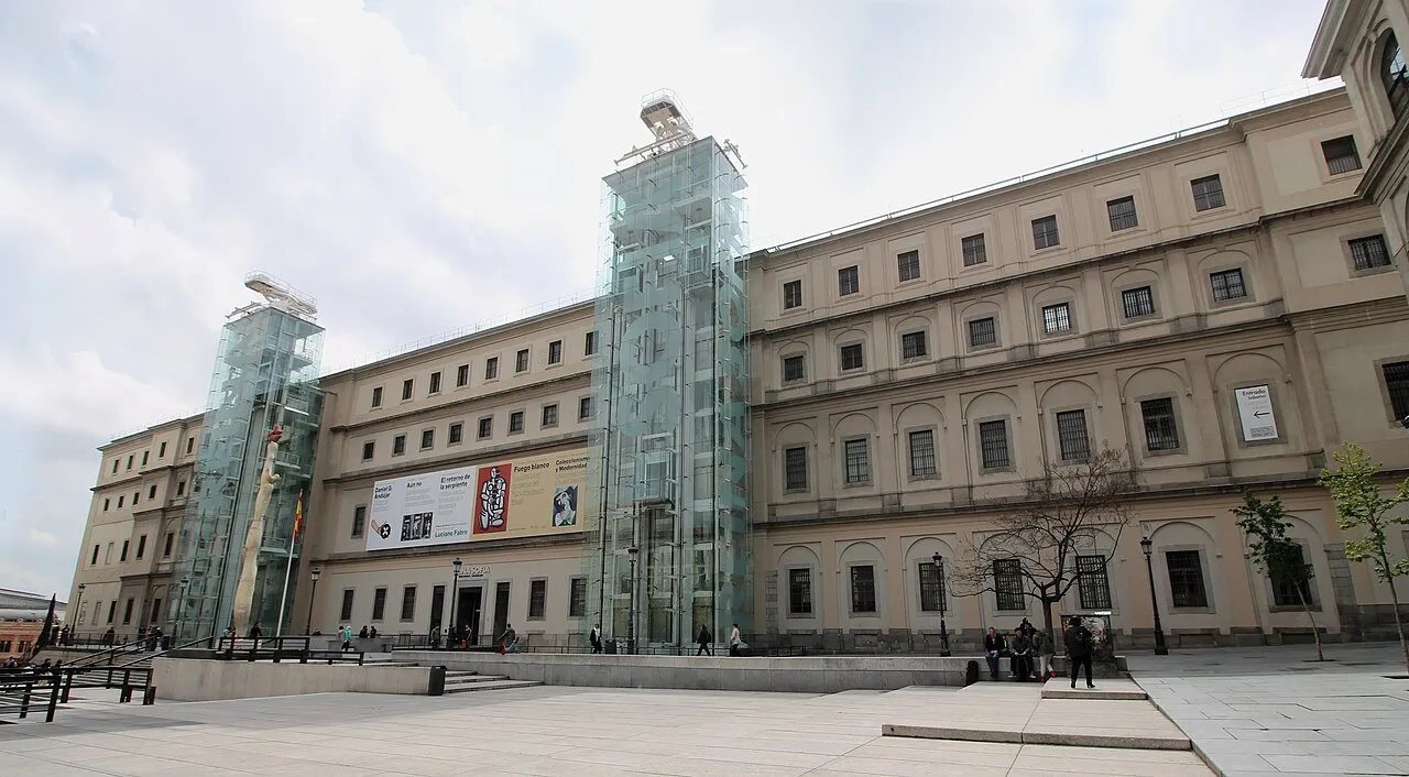 Facade of the Sabatini building of the Reina Sofía Museum, with two glass towers and few visitors.