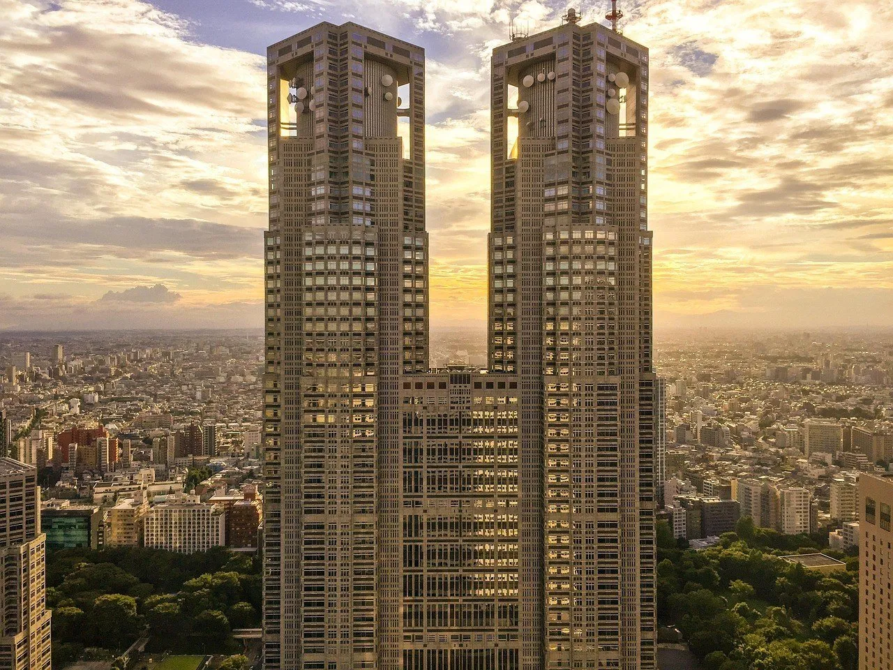 Torres gemelas del Gobierno Metropolitano de Tokio vistas de frente al atardecer, con edificios al fondo.