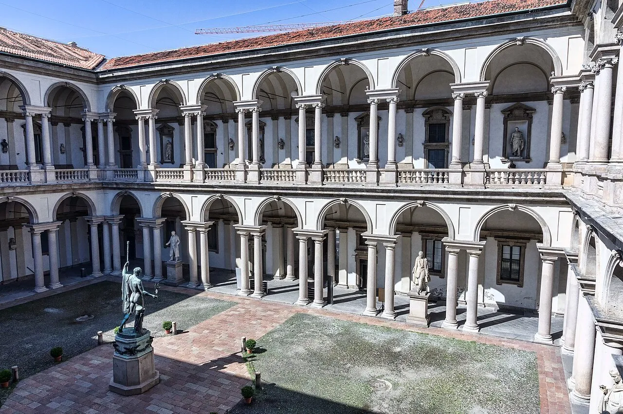 Courtyard of the Palazzo di Brera seen from above, with two-level arcades and a central statue.