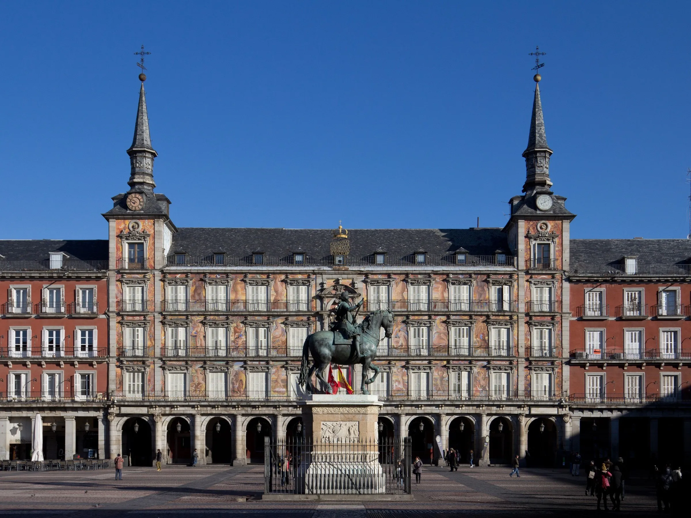 Casa de la Panadería, with two towers and murals, behind an equestrian statue in the Plaza Mayor.