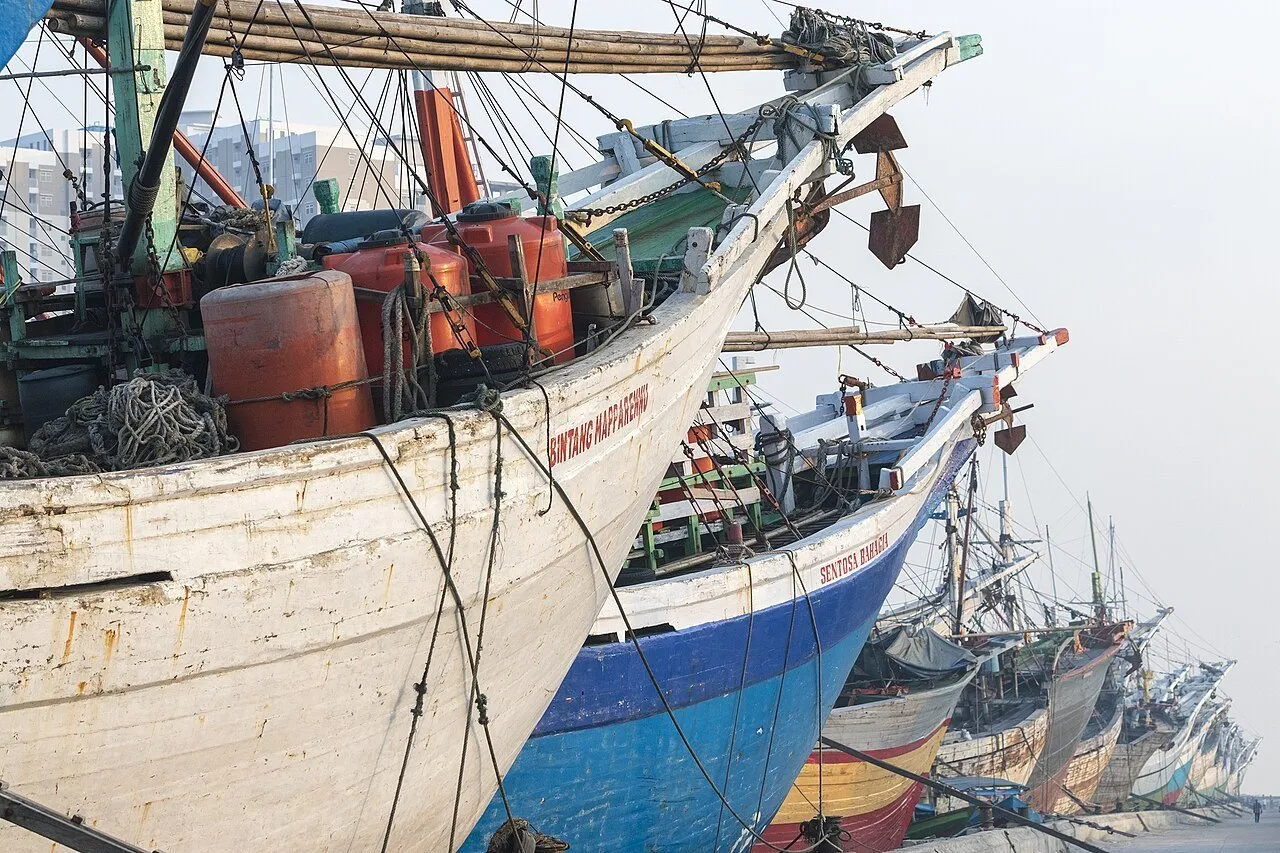 Proas de barcos tradicionais de madeira, pintadas de branco e azul, no porto de Sunda Kelapa.