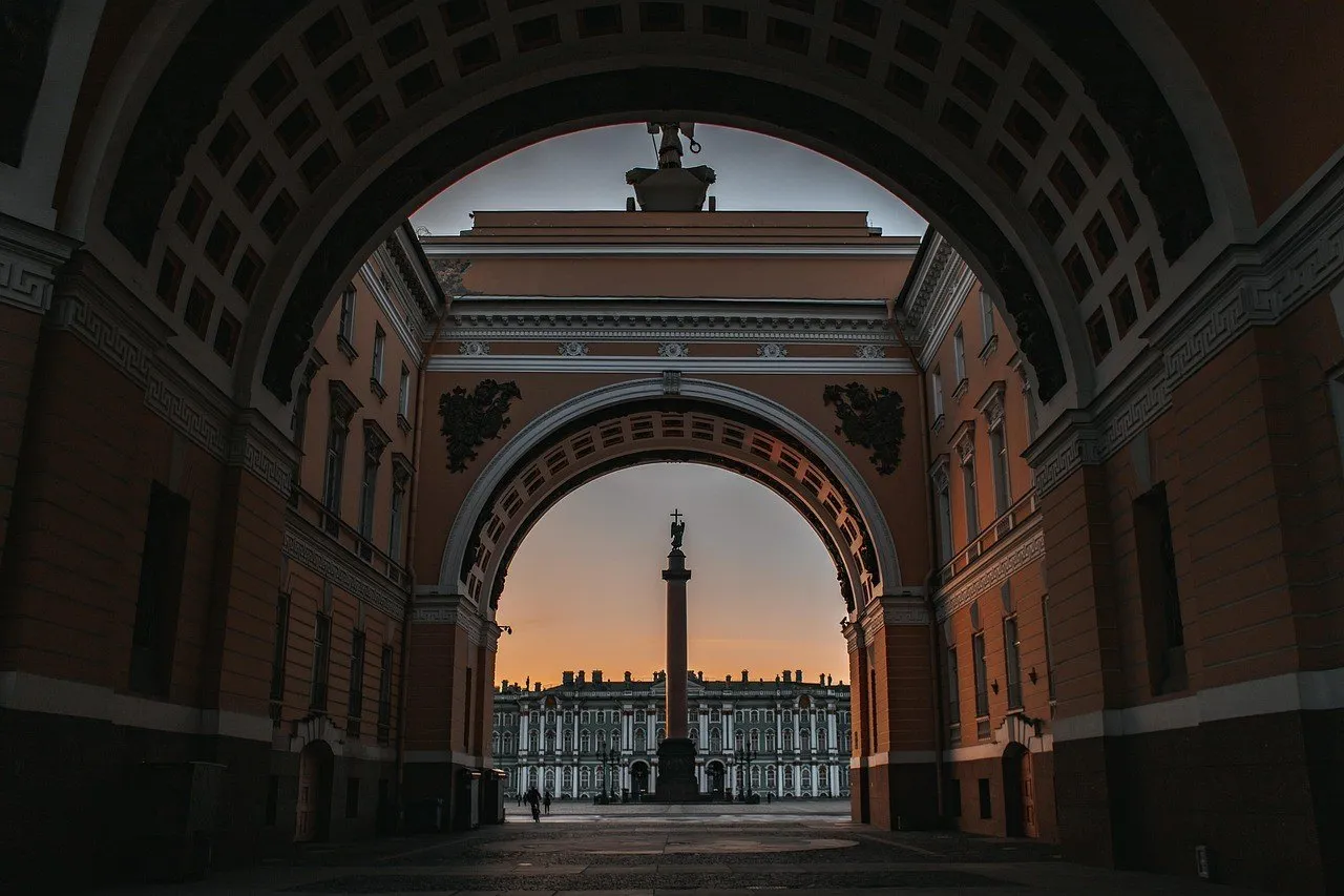 Coluna de Alexandre e Palácio de Inverno vistos através dos arcos do Estado-Maior ao entardecer.