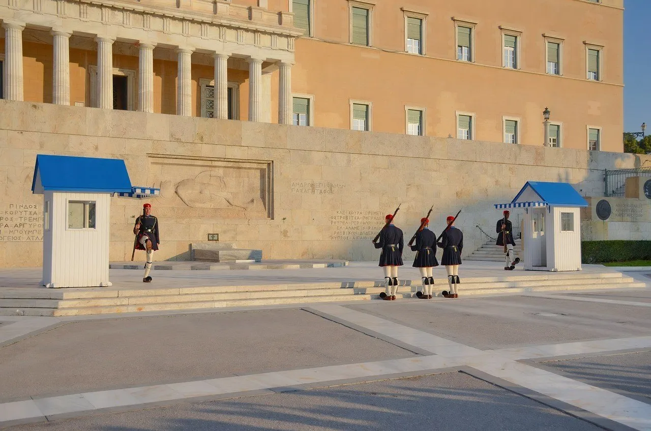 Evzones in ceremony before the Tomb of the Unknown Soldier and the Parliament facade in Athens.