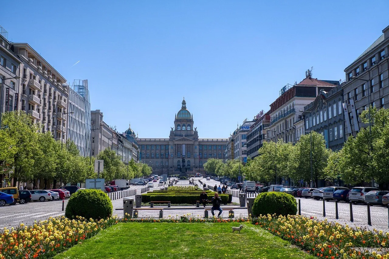 Plaza de Wenceslao con jardines, peatones, estatua ecuestre y la fachada del Museo Nacional al fondo.