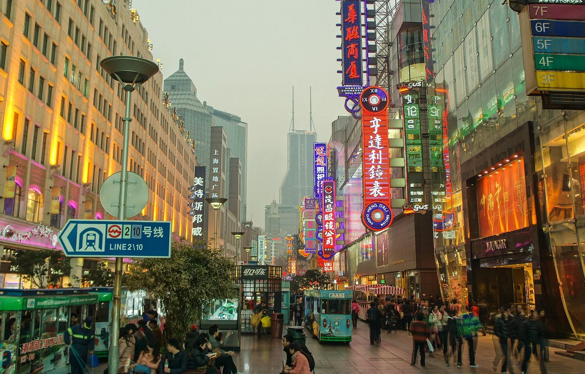 East Nanjing Road with lit signs, commercial facades, tourist vehicles and pedestrians.