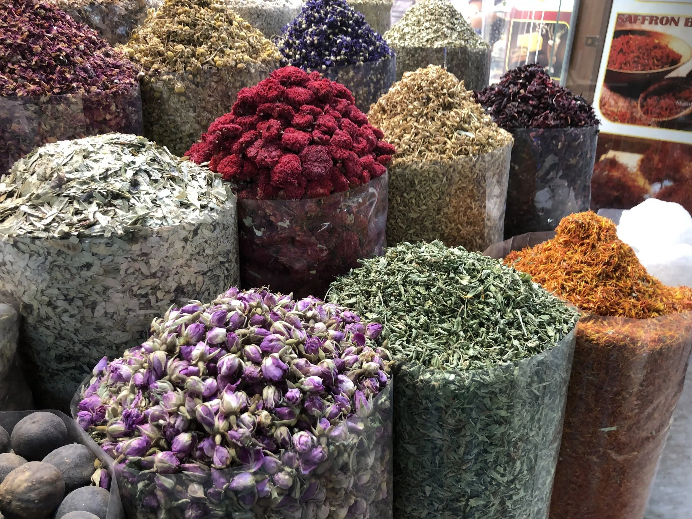 Open sacks of spices, dried flowers and herbs in purple, red, green and orange at a shop in the Deira souk.