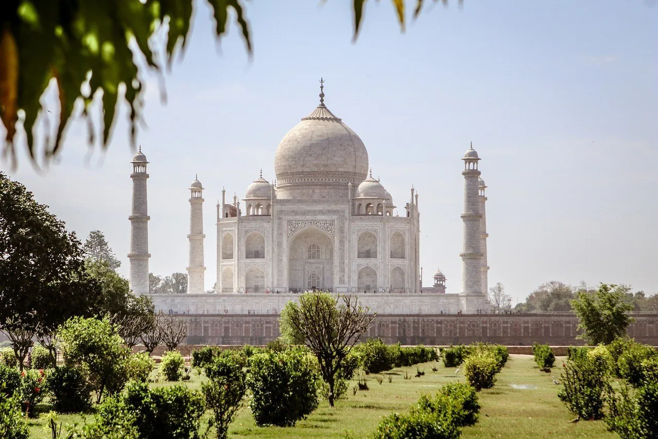 Taj Mahal visto de lado en el jardín, con arbustos y hojas en primer plano.