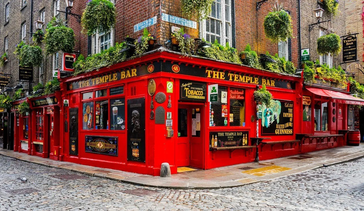 Esquina del pub The Temple Bar, con fachada roja, macetas y calle empedrada casi vacía.