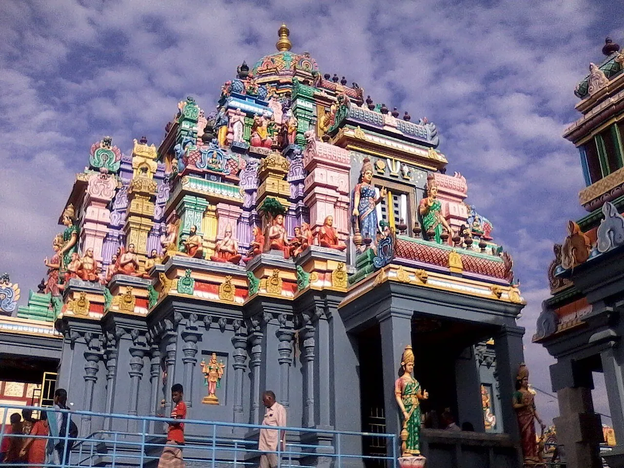 Templo Ashtalakshmi de Besant Nagar, com esculturas coloridas, colunas cinzentas e visitantes na passagem.
