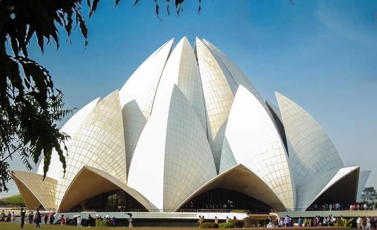 Templo del Loto, en Nueva Delhi, con pétalos de mármol blanco contra el cielo azul y pequeños visitantes a sus pies.