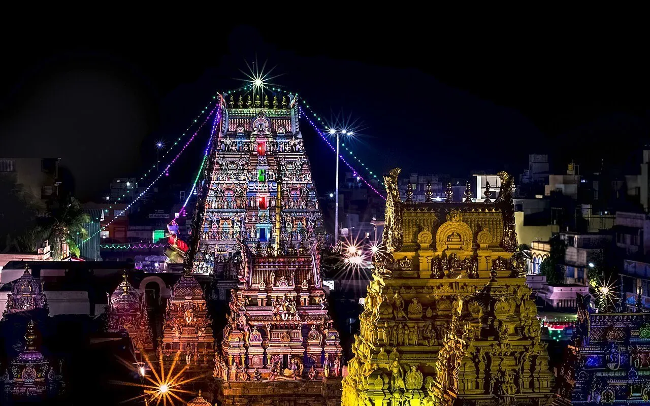 Torres do templo Parthasarathy iluminadas à noite, com cordões de luz colorida e céu escuro.