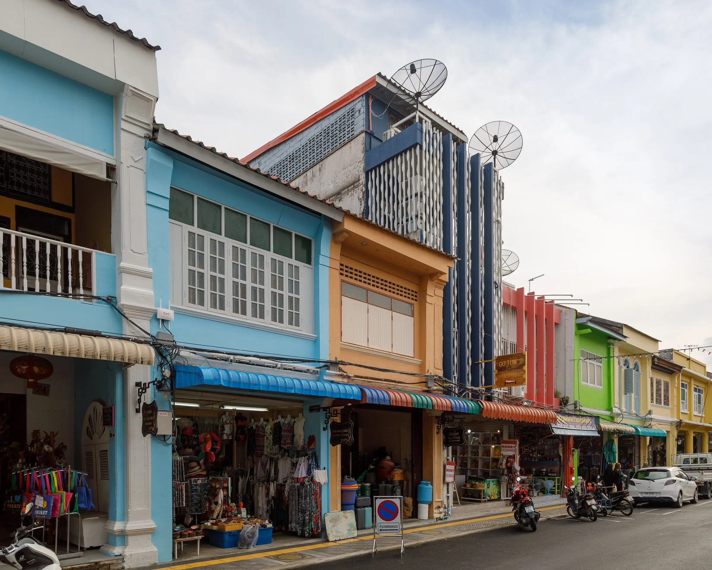 Rua Thalang, na cidade antiga de Phuket, com sobrados coloridos de dois andares, lojas no térreo e motos estacionadas.