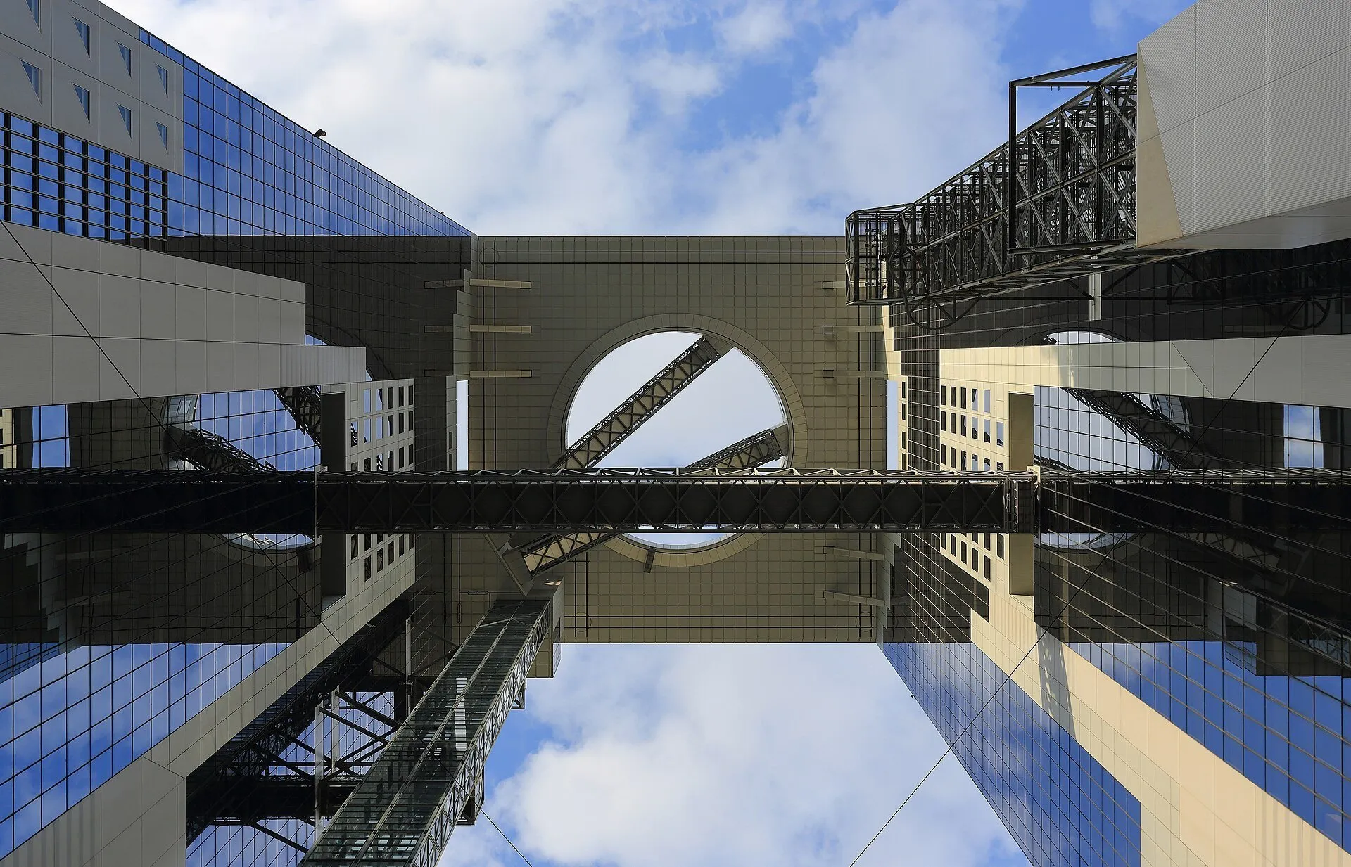 Umeda Sky Building visto de baixo, com duas torres espelhadas, passarelas e abertura circular no alto.