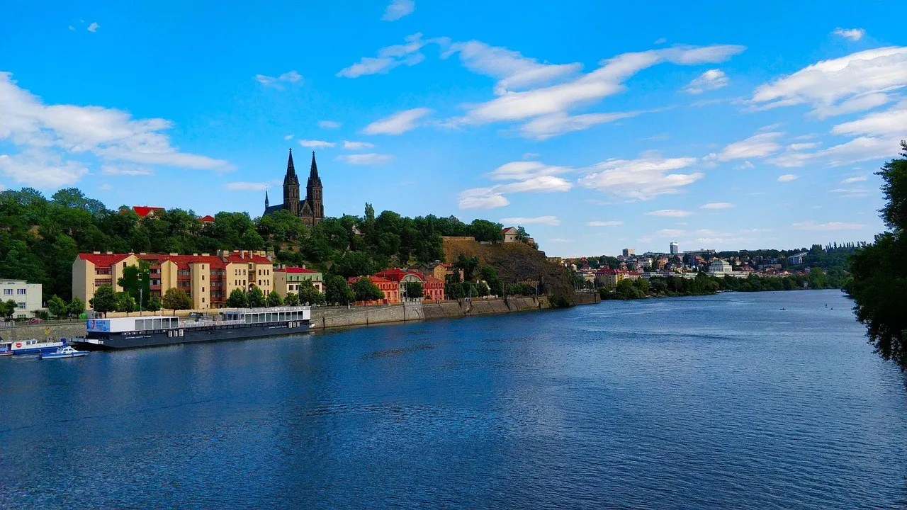 Vyšehrad visto desde el Moldava, con murallas, árboles y las dos torres de la Basílica de San Pedro y San Pablo.
