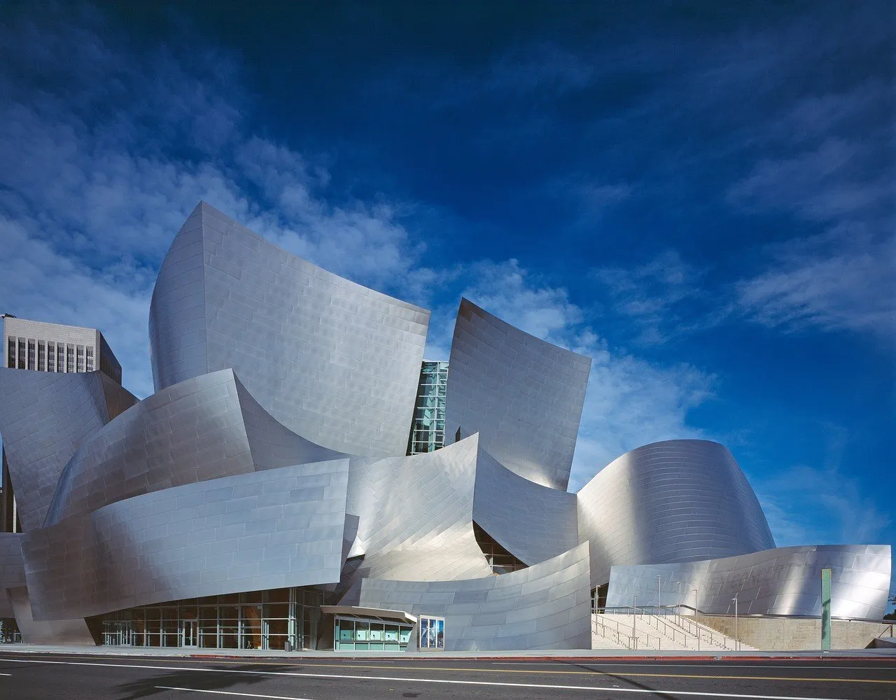 Fachada metálica do Walt Disney Concert Hall, em Los Angeles, vista da rua sob céu azul.