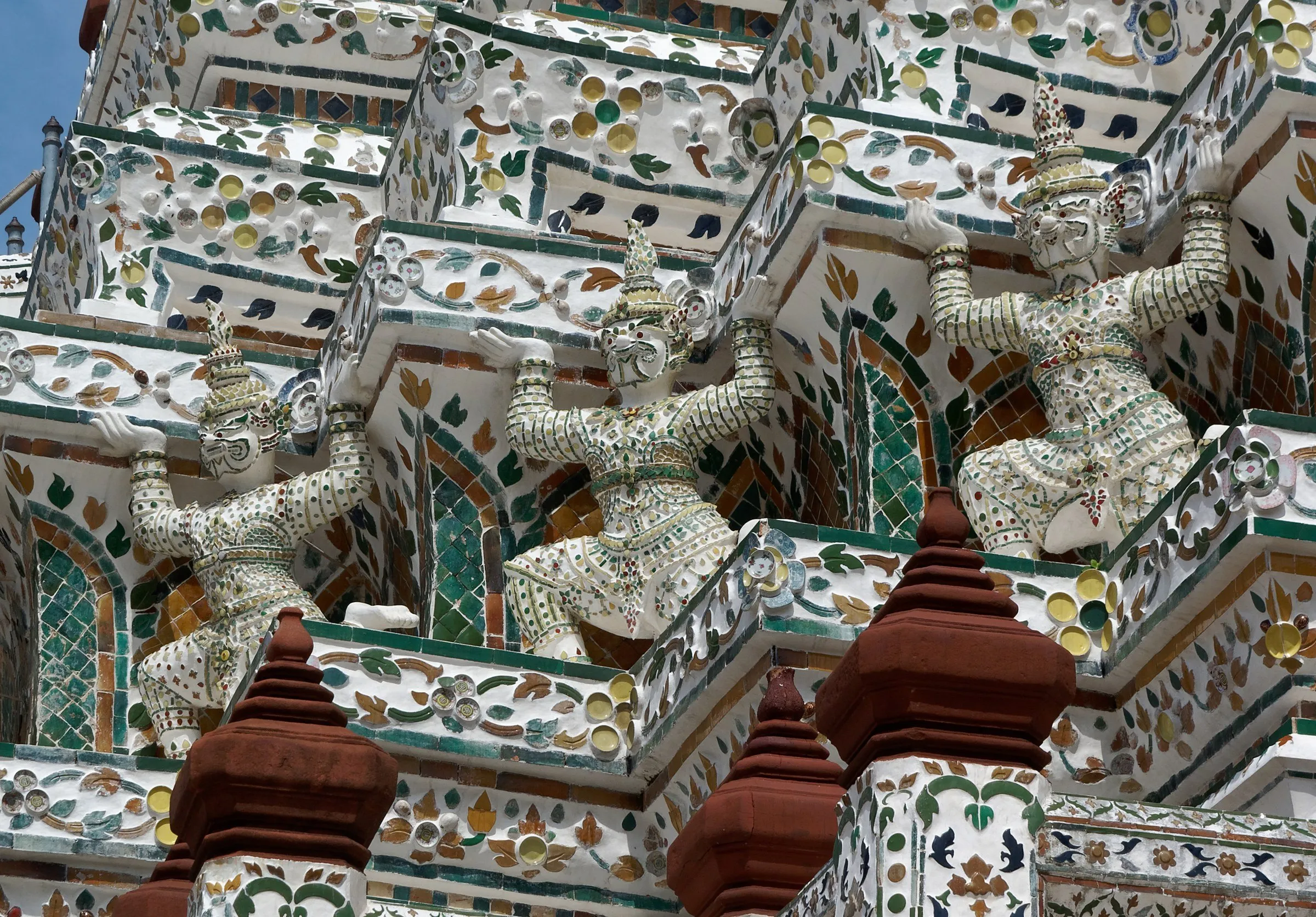 Detalhe do prang do Wat Arun, em Bangkok, com guardiões decorados com porcelana e cacos coloridos em cada nível.