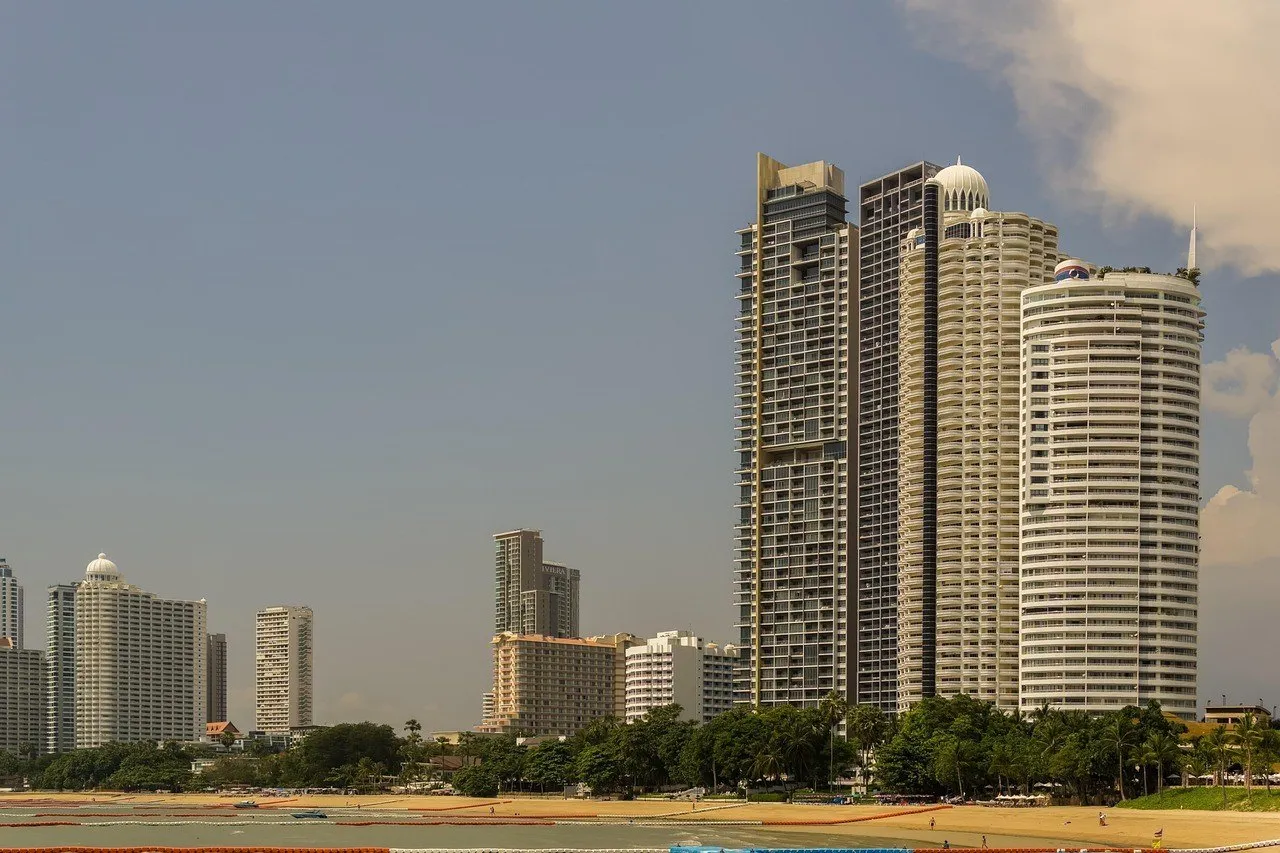 Faixa de areia de Wong Amat com árvores e torres residenciais altas junto ao mar, em Naklua.