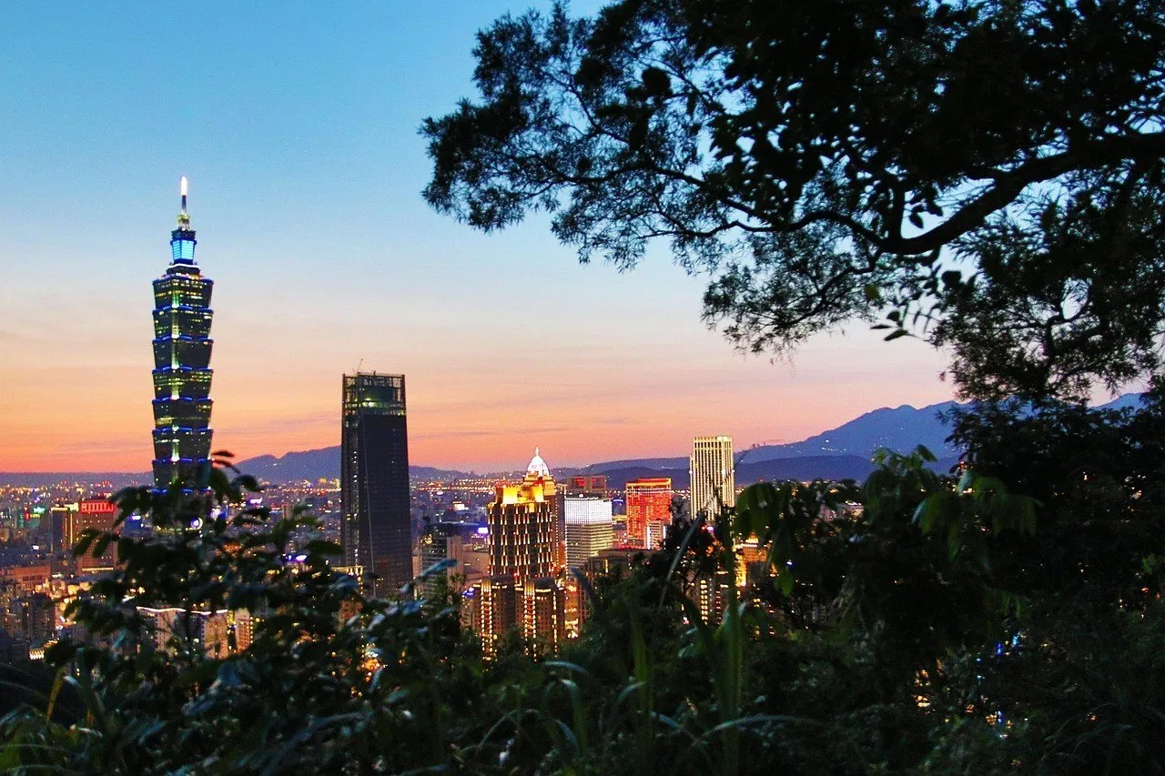 Taipei 101 iluminado ao entardecer, visto entre árvores na Montanha do Elefante.