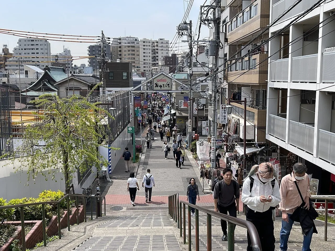 Yanaka Ginza vista desde lo alto de la escalinata, con tiendas, pórtico y peatones repartidos por la calle.