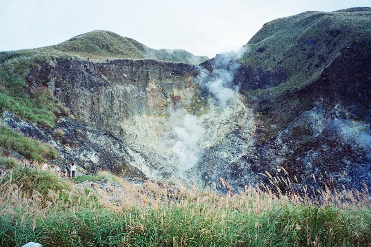 Fumarolas de Xiaoyoukeng entre encostas verdes, rochas e capim no Parque Nacional Yangmingshan.